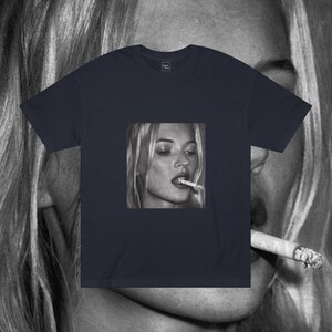 Puede incluir: Una camiseta azul marino con una foto en blanco y negro de una mujer fumando un cigarrillo. La mujer tiene el pelo rubio y lleva una camisa blanca.