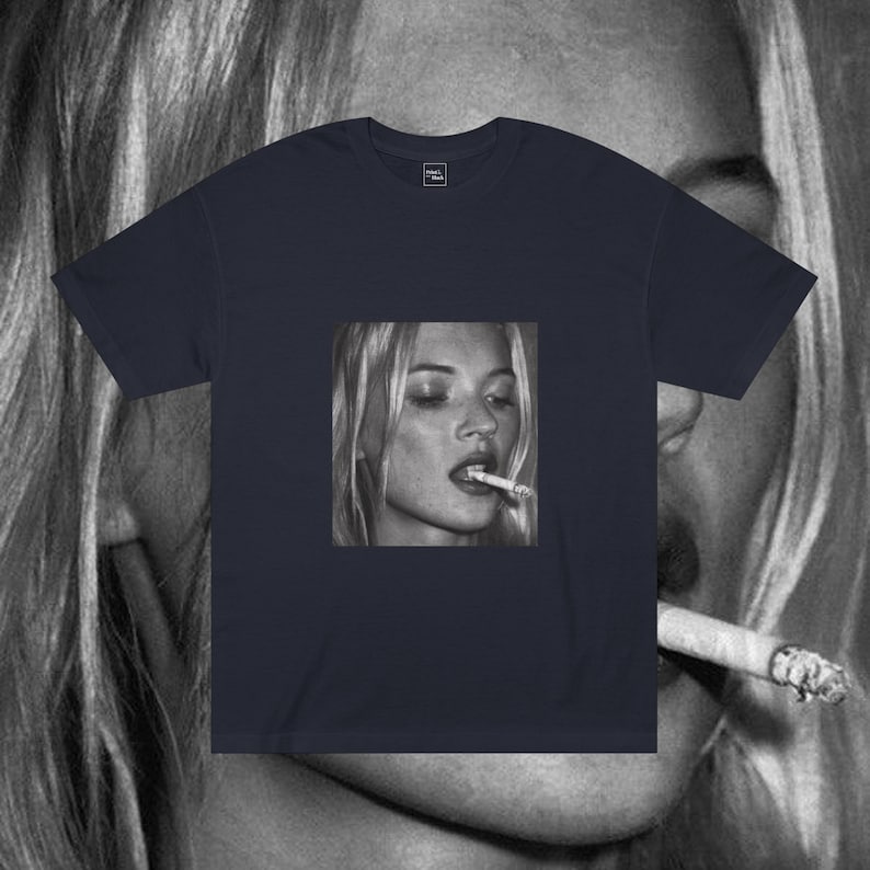 Puede incluir: Una camiseta azul marino con una foto en blanco y negro de una mujer fumando un cigarrillo. La mujer tiene el pelo rubio y lleva una camisa blanca.