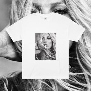 May include: A white t-shirt with a black and white photo of a woman with long hair smoking a cigarette.
