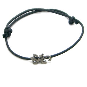 May include: A black cord bracelet with a silver lizard charm.