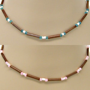 Peut inclure: Deux colliers avec des perles en bois brun et de petites perles d'accent. Le collier du haut a des perles turquoise et blanches, tandis que le collier du bas a des perles roses et blanches.