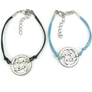 May include: Two bracelets with a silver bike chain gear charm. One bracelet has a black cord and the other has a light blue cord.