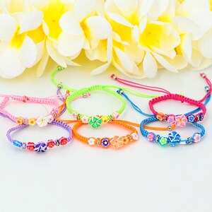 May include: Six colorful friendship bracelets with flower charms. The bracelets are made of braided string and feature different colored flowers.