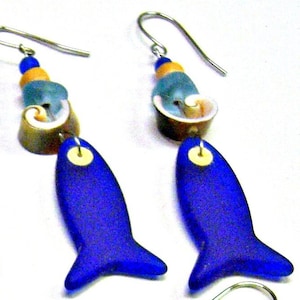 May include: A pair of blue glass fish earrings with silver hooks. The fish have a white and gold bead at the top and are accented with blue and brown glass beads.