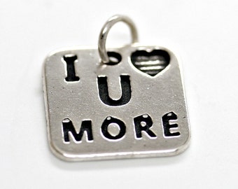May include: Silver charm with a heart and the words "I U MORE" on it.