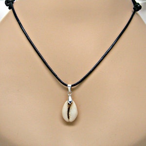 May include: A simple black leather cord necklace with a silver pendant featuring a cowrie shell.