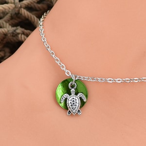 May include: Silver chain anklet with a green turtle charm. The turtle is on a round green disc.