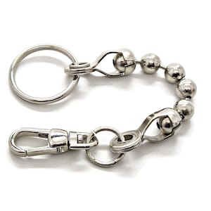 May include: A silver key chain with a round key ring, a swivel clasp, and a beaded chain with a lobster clasp.