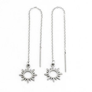 May include: A pair of silver dangle earrings with a sun design. The earrings have a delicate chain and a small sun charm.
