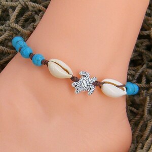 May include: A turquoise and white beaded anklet with a silver turtle charm and shell accents.