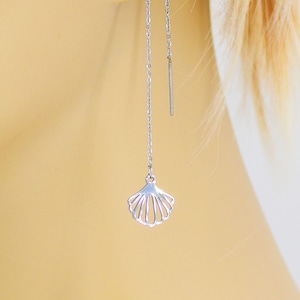 May include: Silver dangle earrings with a seashell charm. The earrings are made of a thin chain and have a simple, elegant design.