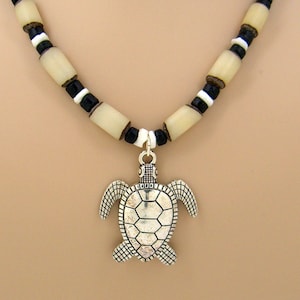 May include: A necklace with white and black beads and a silver turtle pendant.