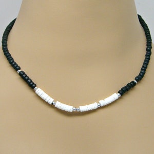 May include: A black and white beaded necklace with silver accents. The necklace is made of small, round beads and has a simple design.