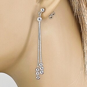 May include: Silver dangle earrings with a chain and multiple small round beads.