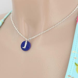 Könnte beinhalten: Eine silberne Kettenkette mit einem blauen runden Anhänger mit einem silbernen Stiefel-Anhänger.