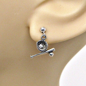 May include: Silver baseball earrings with a baseball glove and bat charm. The earrings are dangle style and have a silver ball at the top.