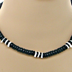 May include: A black and white beaded necklace with a simple design. The necklace is made of small, round beads with alternating black and white colors.