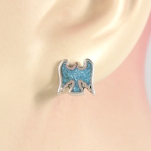 May include: A pair of silver earrings with a turquoise eagle design.