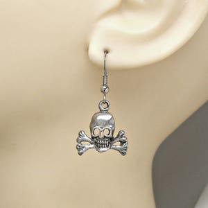 May include: Silver skull and crossbones dangle earrings. The earrings are silver and feature a detailed skull with crossbones.