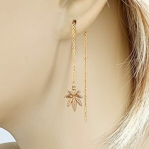 Op de afbeelding: Gouden oorhangers met een bladontwerp. De oorhangers zijn lang en hebben een delicate ketting.