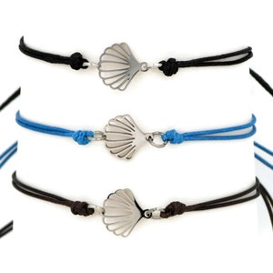 May include: Three adjustable bracelets with a silver seashell charm. The bracelets are made with black, blue, and brown cord.