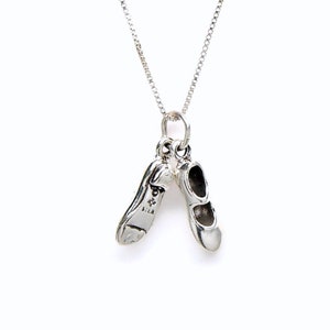 May include: A silver necklace with a charm of two silver ballet shoes.