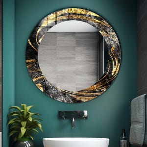 May include: A round decorative mirror with a black, gold, and gray abstract design. The mirror is mounted on a teal wall above a white sink. The bathroom decor includes a plant, faucet, and towel.