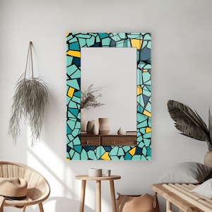 May include: A rectangular mirror with a blue, yellow, and black mosaic frame. The mirror is hanging on a white wall.