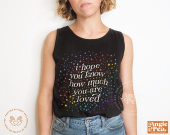 May include: Black tank top with the text "i hope you know how much you are loved" in white script, surrounded by colorful starbursts. The shirt is a casual style.