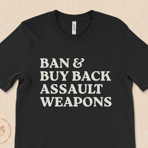 May include: Black t-shirt with white text that reads "Ban & Buy Back Assault Weapons".