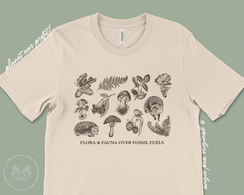 May include: A beige t-shirt with a black and white illustration of various flora and fauna, including mushrooms, berries, ferns, and hedgehogs. The text "FLORA & FAUNA OVER FOSSIL FUELS" is printed below the illustration.