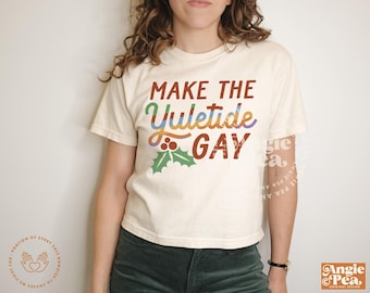 May include: A white t-shirt with the text "Make the Yuletide Gay" in rainbow colours with a red and green holly sprig.