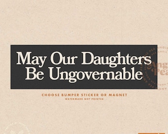 May include: Black and white text on a brown background that reads "May Our Daughters Be Ungovernable".  The text is in a bold, serif font. Below the text is a smaller line of text that reads "Choose Bumper Sticker or Magnet. Watermark Not Printed".  The bottom right corner of the image features a logo with the text "Angie Pea Original Design".