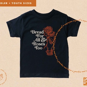May include: A black t-shirt with a graphic design of a rose and the text "Bread For All & Roses Too".