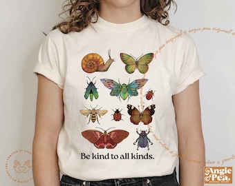May include: White t-shirt with a colorful graphic of various insects and butterflies. The text "Be kind to all kinds." is printed below the graphic.