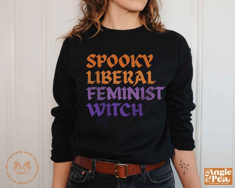 May include: Black sweatshirt with a graphic print that reads "Spooky Liberal Feminist Witch" in orange, yellow, purple, and blue lettering.