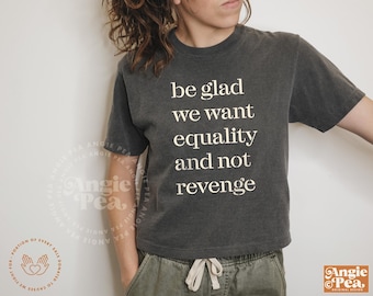 May include: A dark gray cropped t-shirt with the text "be glad we want equality and not revenge" printed in white.