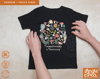 May include: Black toddler t-shirt with a colorful illustration of various mushrooms and plants. The text "Neurodiversity is Necessary" is printed below the illustration. The shirt is held by two hands.