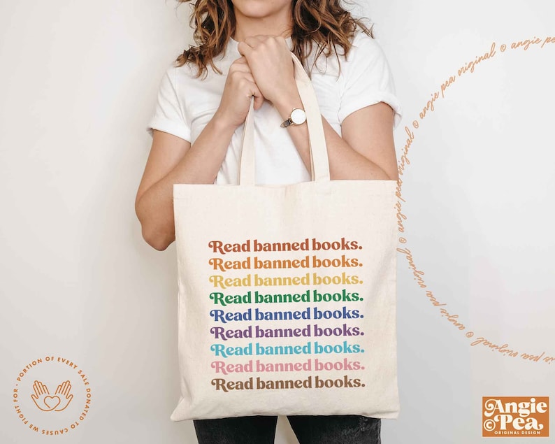 May include: A white tote bag with the text "Read banned books." repeated in rainbow colors. The text is in a retro font style.