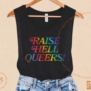May include: A black tank top with the text "RAISE HELL QUEERS!" in rainbow colors.