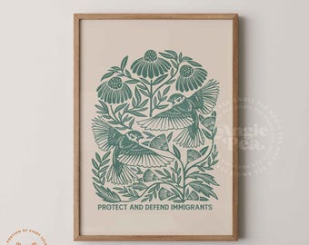 May include: A framed art print featuring a teal illustration of two birds in flight amidst floral elements. The text "PROTECT AND DEFEND IMMIGRANTS" is at the bottom. The artwork is set against a cream background.