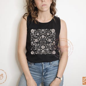 May include: Black tank top with a floral design and the text "Be brave, be loud, and look out for others".