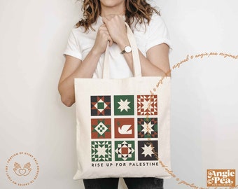 Könnte beinhalten: Eine weiße Einkaufstasche mit einem Patchwork-Muster in Grün, Rot und Schwarz. Die Tasche trägt den Aufdruck "Rise Up For Palestine" auf der Vorderseite.