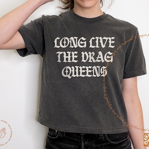 May include: A dark grey cropped t-shirt with the text "LONG LIVE THE DRAG QUEENS" printed in white. The text is in a gothic font.
