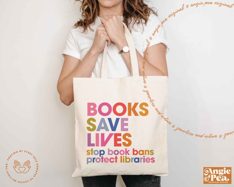 Puede incluir: Una bolsa de tela blanca con el texto "BOOKS SAVE LIVES stop book bans protect libraries" en letras de colores. La bolsa est&aacute; siendo sostenida por una persona.