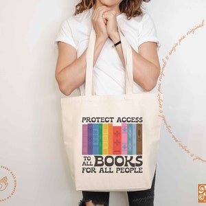 K&ouml;nnte beinhalten: Eine wei&szlig;e Einkaufstasche mit dem Aufdruck "Protect Access to All Books for All People". Der Text ist schwarz und die Tasche zeigt einen regenbogenfarbenen Stapel B&uuml;cher.