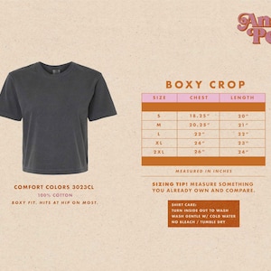 May include: A size chart for a boxy crop top, made of 100% cotton. The chart shows the chest and length measurements in inches for sizes S, M, L, XL, and 2XL. The text "BOXY CROP" is at the top of the chart. The text "COMFORT COLORS 3023CL" is below the image of the shirt. The text "BOXY FIT. HITS AT HIP ON MOST." is below the text "COMFORT COLORS 3023CL".