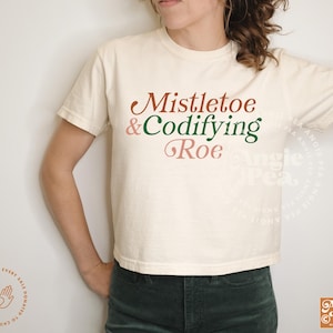May include: A white t-shirt with the text "Mistletoe & Codifying Roe" in green, pink, and brown lettering.