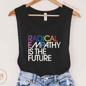 May include: Black tank top with the text "RADICAL EMPATHY IS THE FUTURE" in rainbow colors.