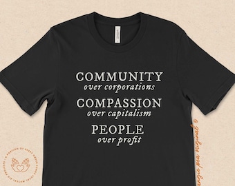 May include: Black t-shirt with white text that reads "COMMUNITY over corporations COMPASSION over capitalism PEOPLE over profit".